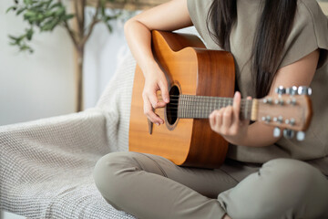 Fototapeta premium Music and Relaxation. Young woman playing acoustic guitar at home.