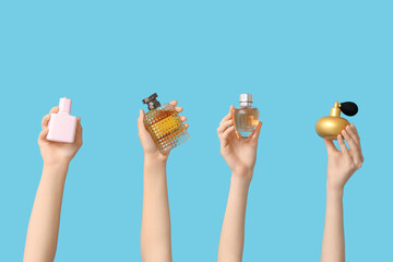 Female hands with different bottles of perfume on blue background