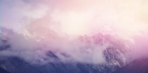 Clouds covering snowcapped mountains against sky