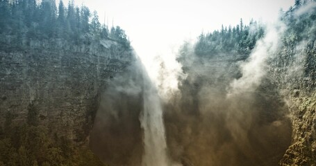 Flat design waterfall scene is showing backlit cascade plunging into canyon, with evergreen trees