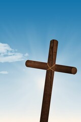 Flat design is showing rope-bound wooden cross standing in blue sky with sun rays, small cloud