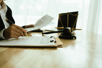 Lawyer sitting at desk in modern office reviewing and signing legal documents related to finance, equity and contractual agreements in business law.