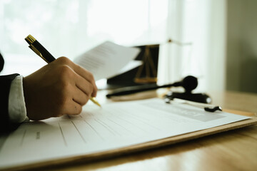 Lawyer sitting at desk in modern office reviewing and signing legal documents related to finance, equity and contractual agreements in business law.