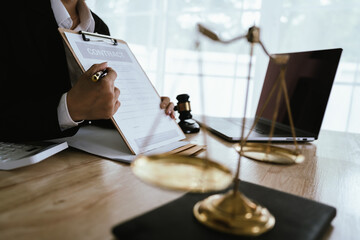 Lawyer sitting at desk in modern office reviewing and signing legal documents related to finance, equity and contractual agreements in business law.