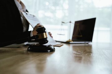 Lawyer sitting at desk in modern office reviewing and signing legal documents related to finance, equity and contractual agreements in business law.
