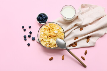 Napkin, berries, bowl with cornflakes and milk on pink background