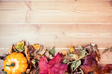 Pumpkins surrounded by leaves on wooden table