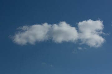 Elongated white cloud formation is stretching across deep blue sky in flat design, copy space