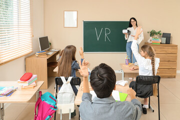 Female teacher with VR glasses conducting lesson to pupils in classroom