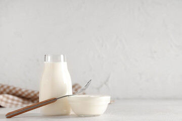 Glass bowl and bottle of tasty yogurt on white background