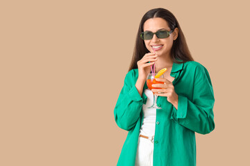 Young woman in sunglasses with aperol spritz cocktail on beige background
