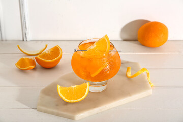 Glass of Aperol spritz cocktail and oranges on white wooden table