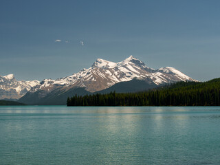 Calm turquoise waters of Maligne Lake reflect snowy peaks in Jasper National Park, Alberta. A peaceful landscape from the heart of the Canadian Rockies.