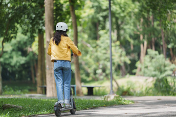 Woman riding electric scooter in green park wearing helmet