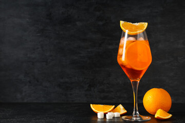 Glass of Aperol spritz cocktail with fruits and sugar on black background