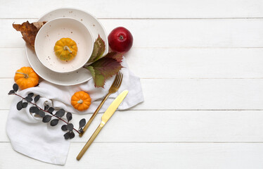 Beautiful table setting with pumpkins and autumn leaves on white wooden background