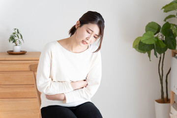 腹痛でお腹を押さえる女性
