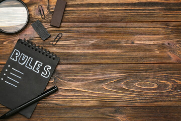 Notebook with blank list of rules and stationery on wooden background