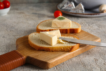 Wooden board of bread slices with triangles of tasty processed cheese and tomatoes on grey...