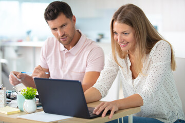couple managing finances reviewing their bank accounts using laptop computer
