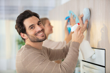 handsome young man wiping kitchen cabinets