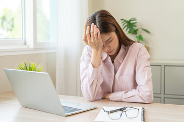 Stressed, exhausted asian young woman having migraine symptoms headache, bored sitting work long...