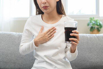 Acid reflux disease, suffer asian young woman, girl hand holding a glass of cola, have symptom...