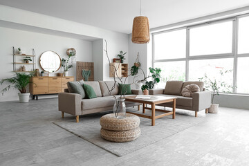 Interior of stylish living room with cozy grey sofas, coffee table and houseplants