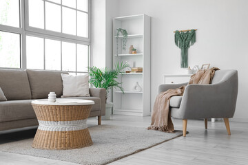 Interior of living room with soft couch, armchair and rattan table