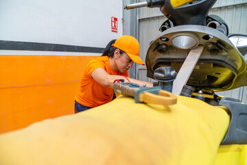 Female mechanic using digital multimeter checking motorcycle battery voltage
