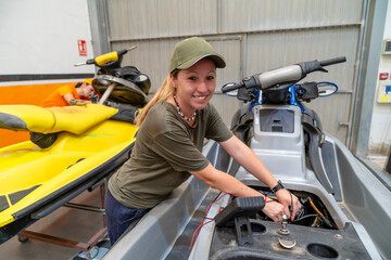 Female mechanic repairing personal watercraft engine in workshop