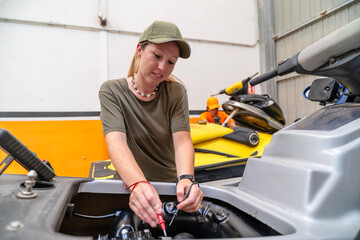 Female mechanic repairing jet ski engine in workshop