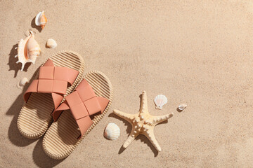 Composition with stylish flip-flops, seashells and starfish on sand as background