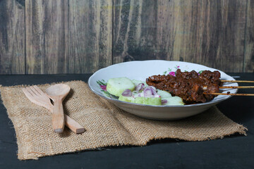 Indonesian traditional food chicken satay and lontong served on a glass plate