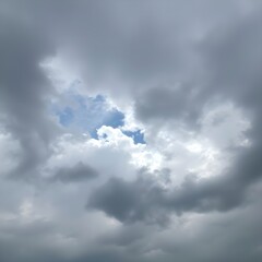 Fototapeta premium The first patch of blue sky cracking through heavy clouds.