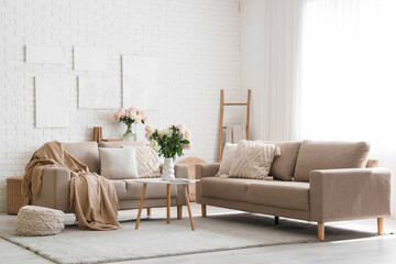 Interior of stylish living room with grey sofas, coffee table and beautiful peonies