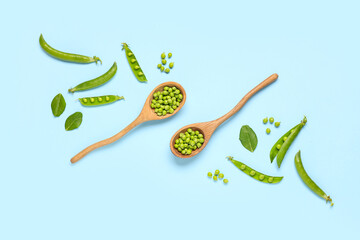 Wooden spoons with fresh green peas on blue background
