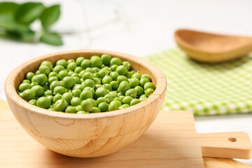 Wooden bowl with fresh green peas on white background, closeup