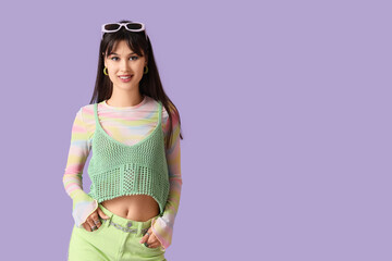 Stylish young woman with sunglasses on lilac background