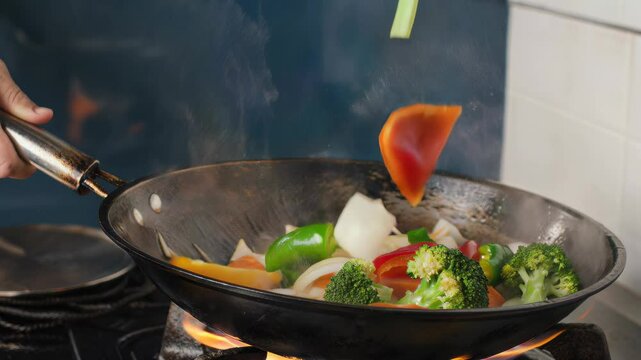 Fresh colorful stir fry vegetables sautéing in a wok on the gas stove preparing a healthy nutritious meal