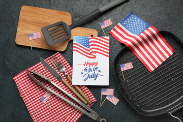 USA flags, greeting card with text HAPPY 4TH OF JULY and barbecue utensils on black grunge...