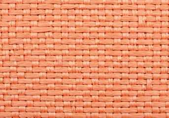 Fototapeta premium Detailed Close-Up of a Woven Coral-Colored Fabric Texture: A Study in Intertwined Threads
