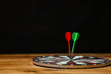 Fototapeta premium Board with darts on wooden table against dark background
