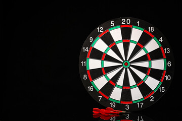 Board and darts on dark background