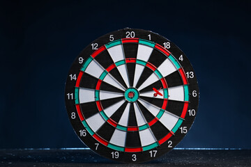 Board with dart on dark background