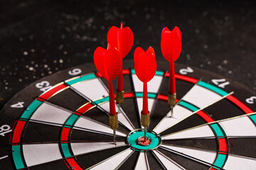 Board with darts on dark background, closeup