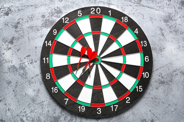 Board with darts on grey grunge background