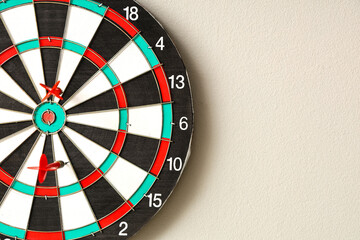 Board with darts hanging on light wall