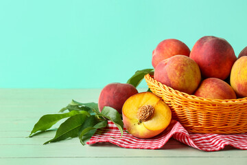 Wicker basket of fresh peaches on turquoise background