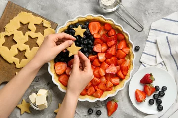 Fototapeten Woman making tasty American flag pie on grey grunge table. Independence Day celebration © Pixel-Shot